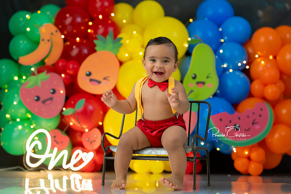 Rainbow Fruit Bash backdrop with colorful balloons and smiling fruit faces
