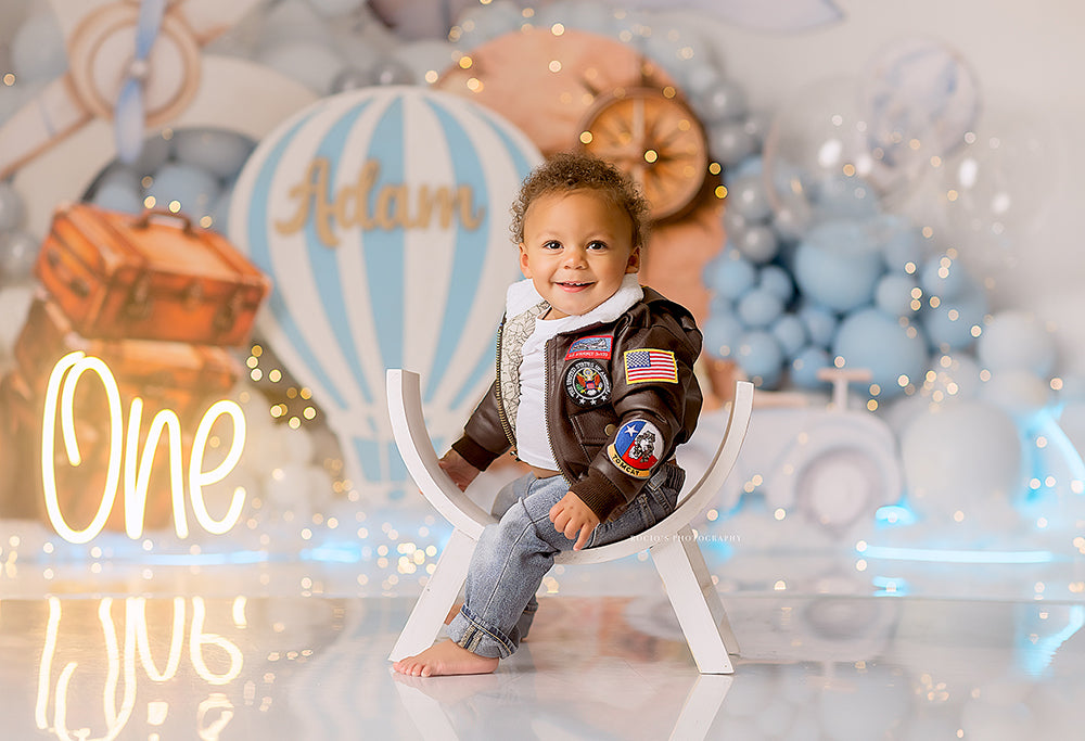 Adventure Awaits backdrop with hot air balloons, blue balloons, airplane, and suitcases