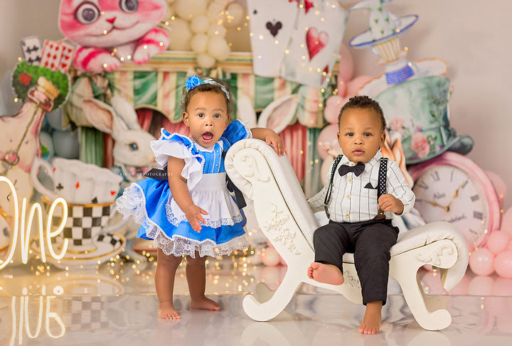 Wonderland Whimsy Alice-inspired photo backdrop with Cheshire Cat, tea party props, and pastel balloons.