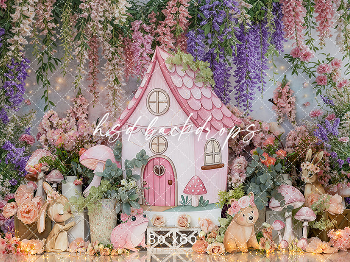 Enchanted Sprout Cottage photography backdrop with pink fairy house, florals, and woodland animals for cake smash and milestone photo sessions.