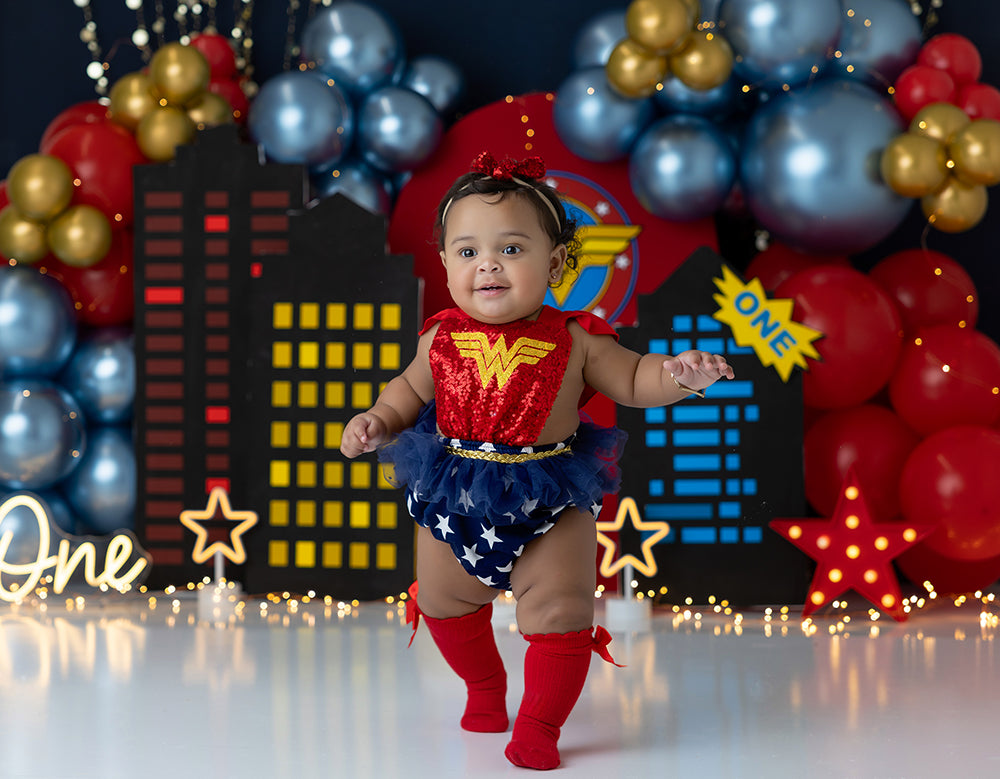 Super City Smash superhero photography backdrop with city buildings, red and blue balloons, and star accents for cake smash and birthday photos.
