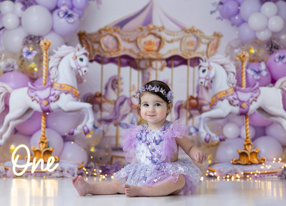 Lilac and Gold Carousel backdrop with whimsical carousel horses, pastel balloons, and fairytale birthday photo setup.