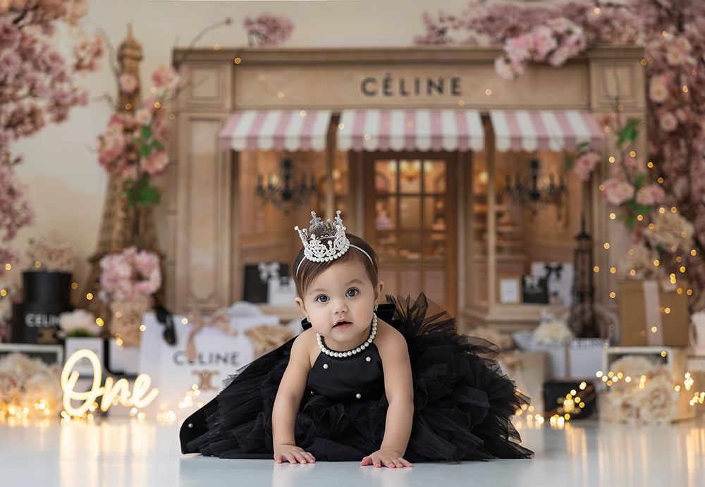 La Petite Couture Parisian boutique birthday backdrop with cherry blossoms, Eiffel Tower décor, couture gift boxes, and elegant blush styling for photography sessions.