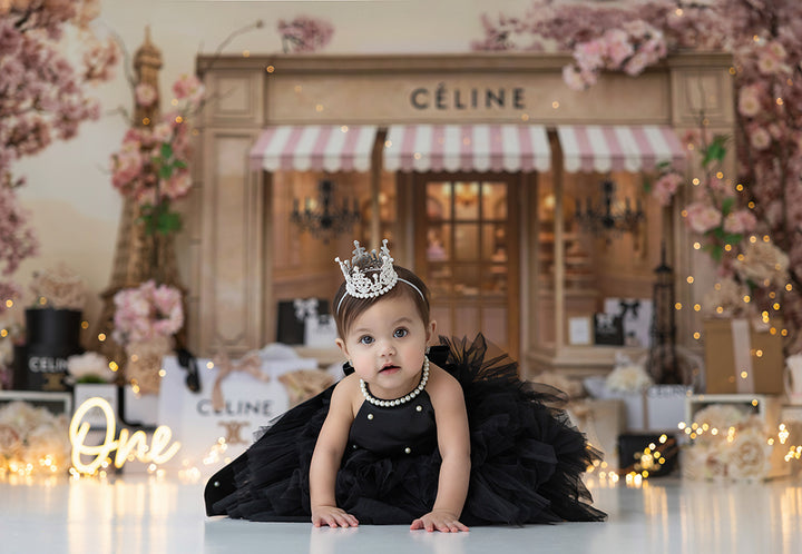 La Petite Couture Parisian boutique birthday backdrop with cherry blossoms, Eiffel Tower décor, couture gift boxes, and elegant blush styling for photography sessions.