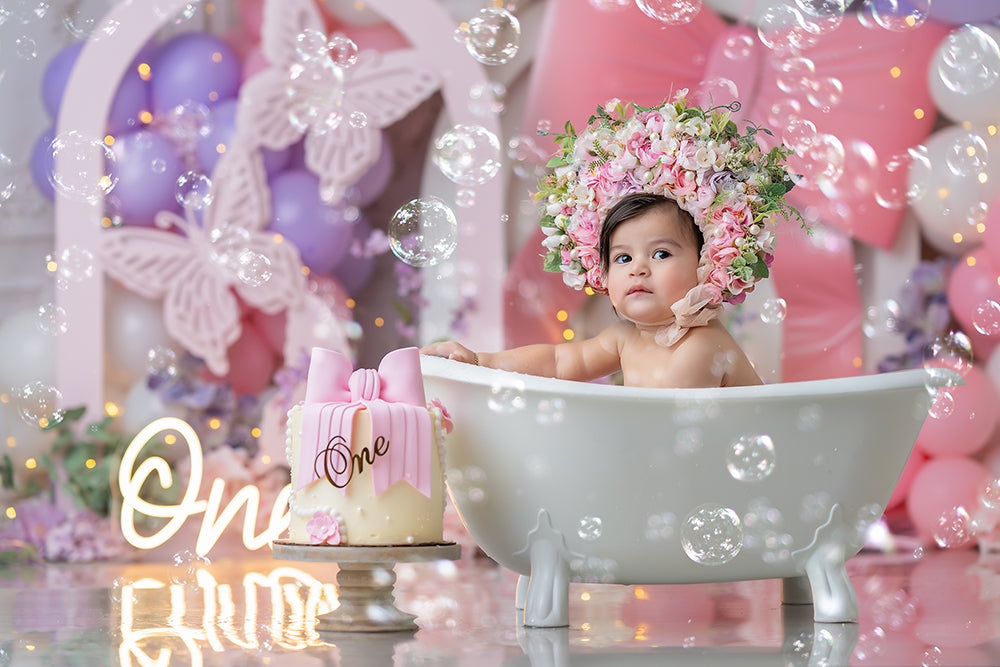 Blush butterfly bow photography backdrop with pastel balloons, florals, and whimsical spring decorations for children’s portraits and cake smash sessions