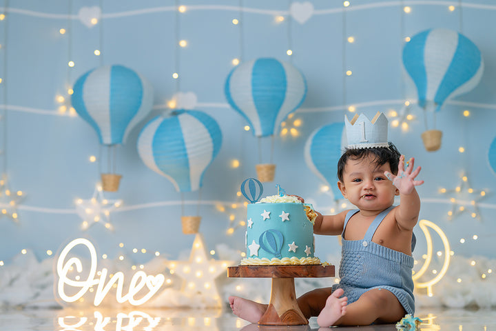 Blue Sky Balloon Adventure photography backdrop with blue and white hot air balloons, glowing stars, clouds, and pastel boy birthday scene – HSD Backdrops.