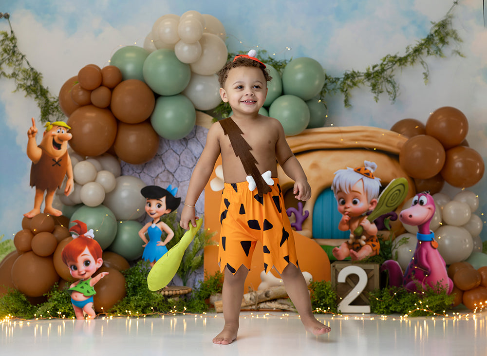 Prehistoric stone age bone house cake smash photography backdrop with balloon clusters, playful first birthday portrait background.