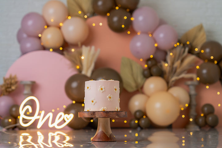 Blush mocha balloon arch cake smash photography backdrop with modern boho birthday styling and neutral tones.