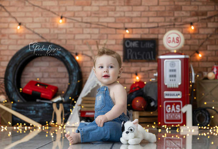 Vintage garage boys cake smash photography backdrop with retro gas station pump and brick wall birthday scene.